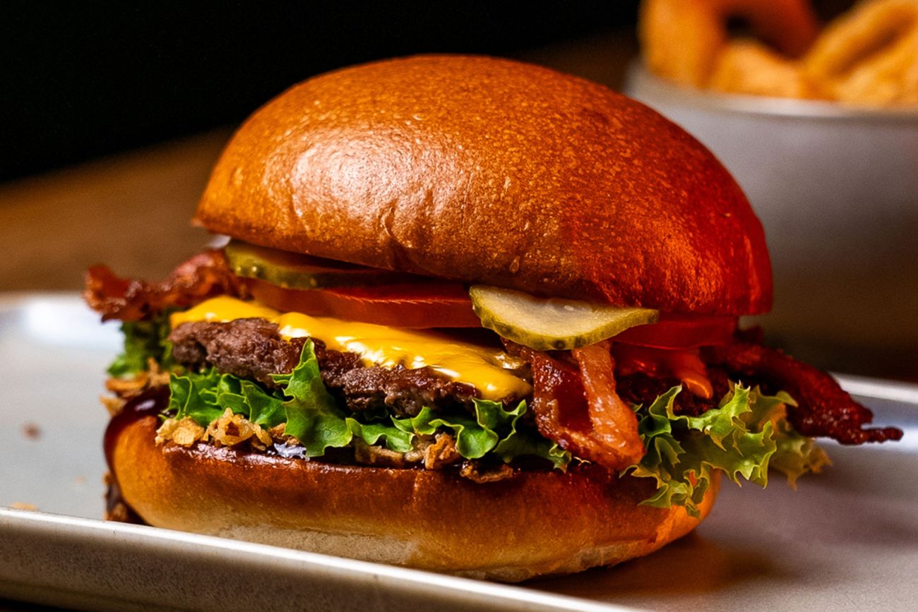 Dame geniesst unseren Burger mit frischem Schweizer Bun