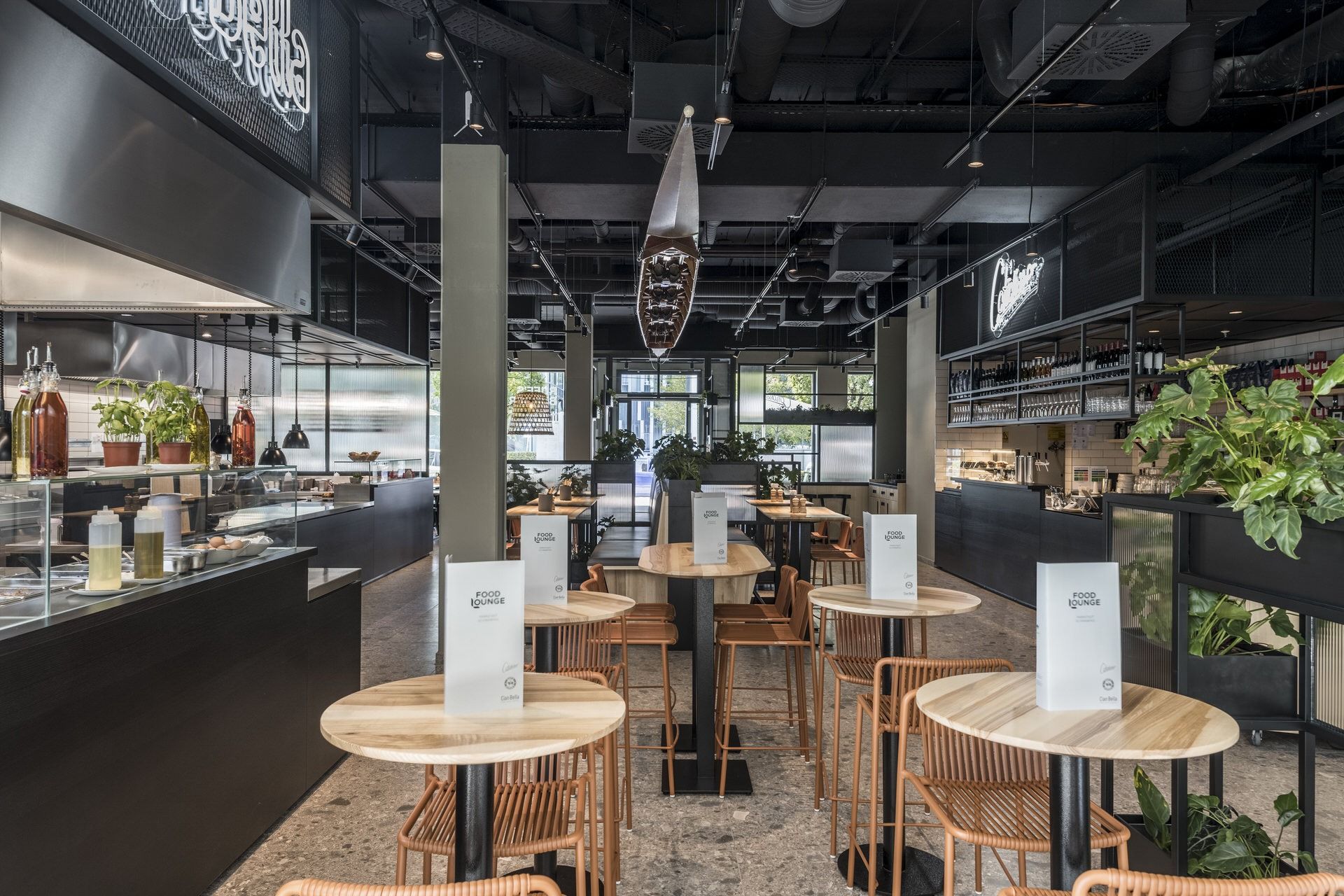 Innenansicht von "Ruff's Burger" mit Barbereich, Hochstühlen, Pflanzen, offener Küche und modernen schwarzen Deckenelementen.