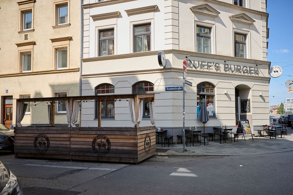 Außenansicht auf das Restaurant Ruff's Burger mit Sitzgelegenheiten auf dem Gehsteig