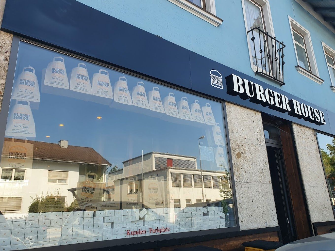 Außenansicht von "Burger House" mit großem Schaufenster, dekoriert mit "Burger House" ToGo-Tüten.
