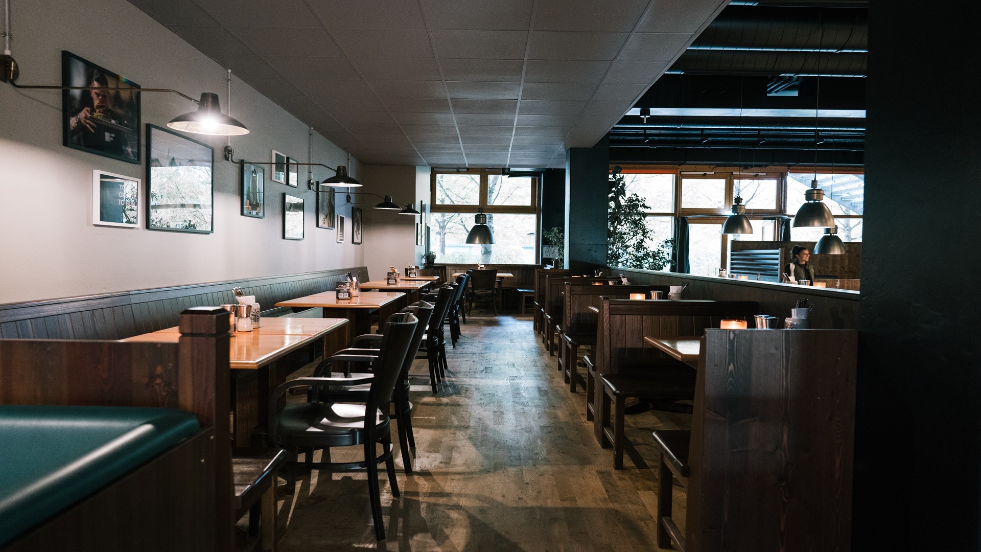 Innenansicht von "Ruff's Burger" mit Reihen von Sitznischen, Holztischen, dunklen Holztrennwänden, Wandbildern und Hängelampen.