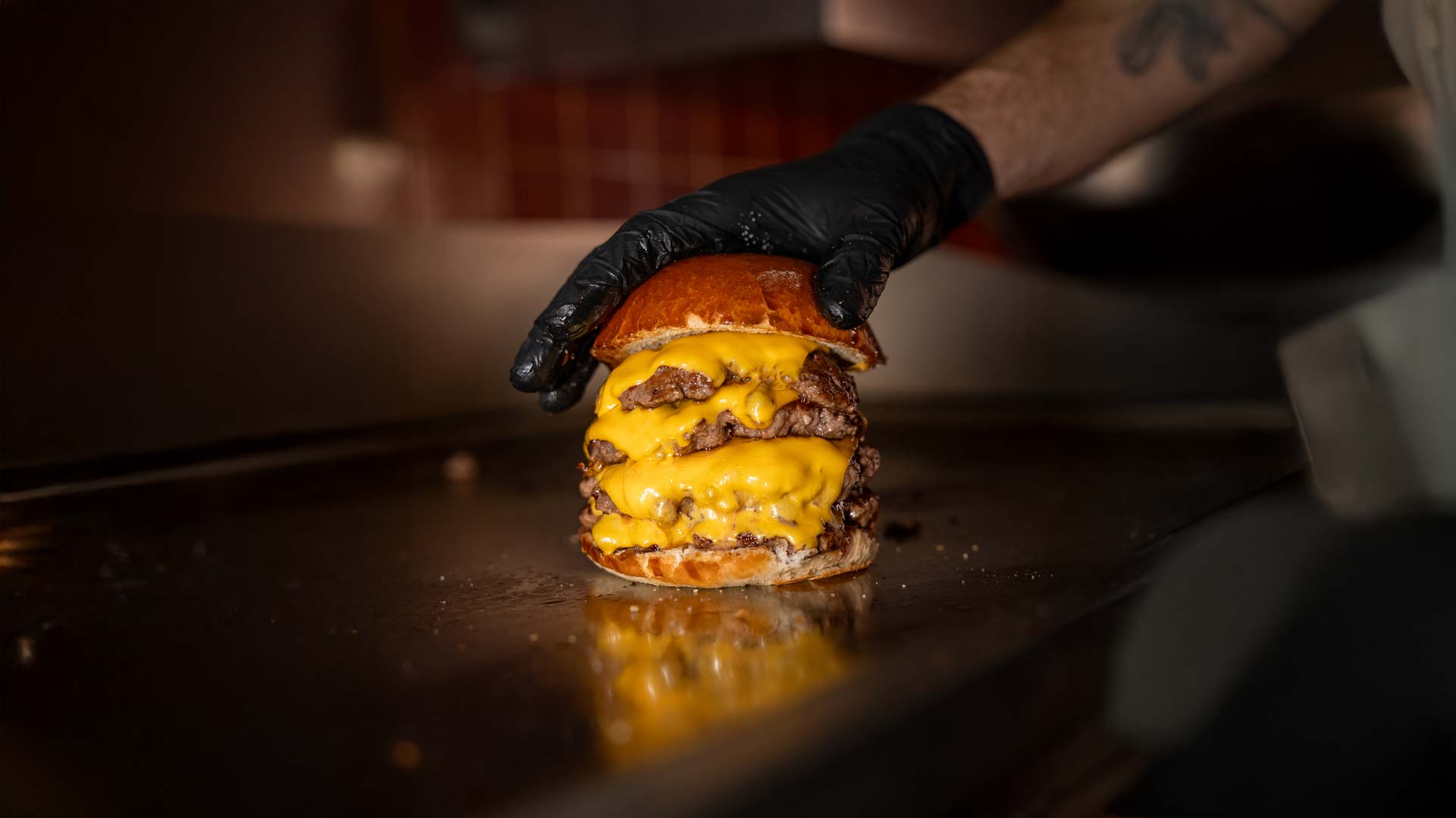 Ein Cheeseburger auf einer Grillplatte mit mehreren Patties, geschmolzenem Käse und Brioche-Bun.