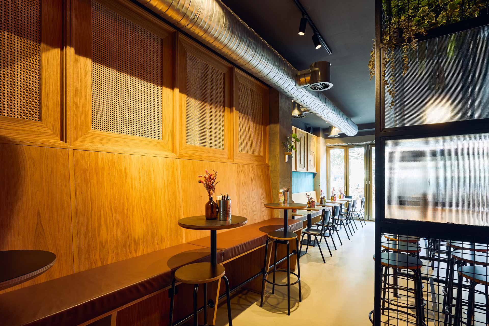 Innenansicht von "Ruff's Burger" mit Holztischen, gelben Gittern, Barbereich, Neon-Elementen und offener Raumaufteilung.